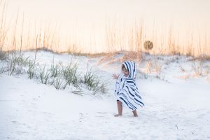 Toddler boy walking on a beach with a sunset